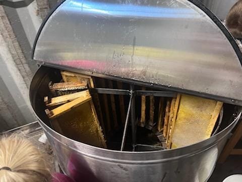 Beehive extractor showcasing honey-filled frames inside, used for extracting honey from honeycombs in beekeeping.